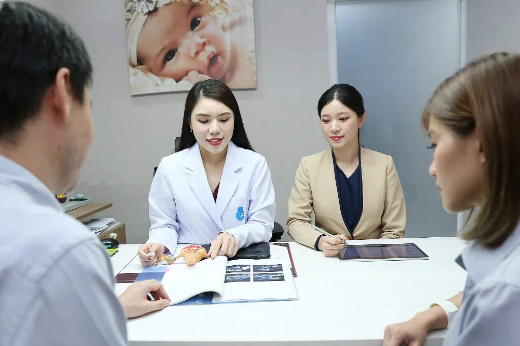 Couple in a fertility consultation with a doctor reviewing ultrasound scans